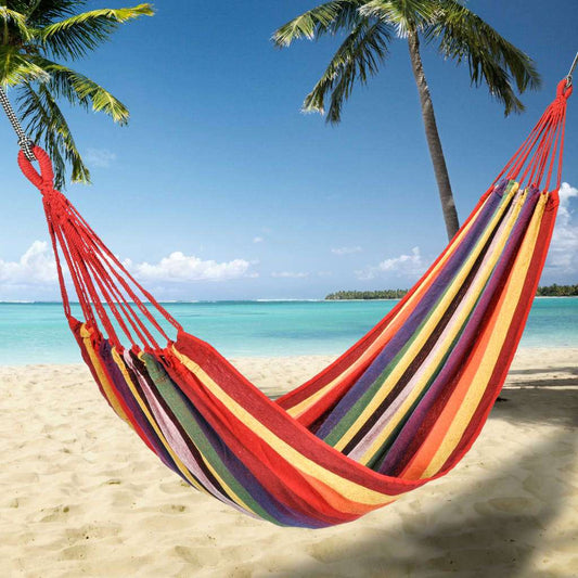 Colorful HI single cotton hammock hanging in a garden with storage bag